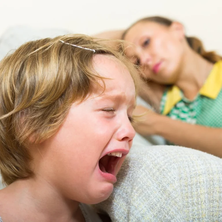 a child cries while her tired mother watches nearby