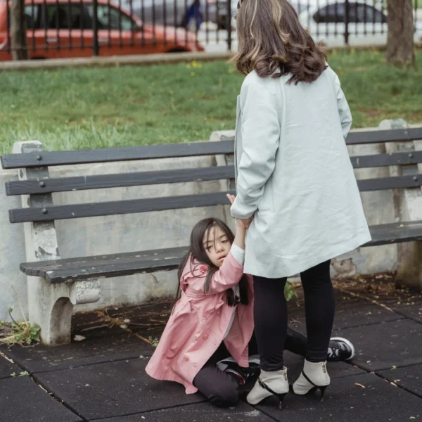 a mother holds her daughter, who is sitting on the ground