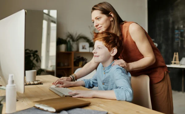 A mother teaching son about time management on a computer.