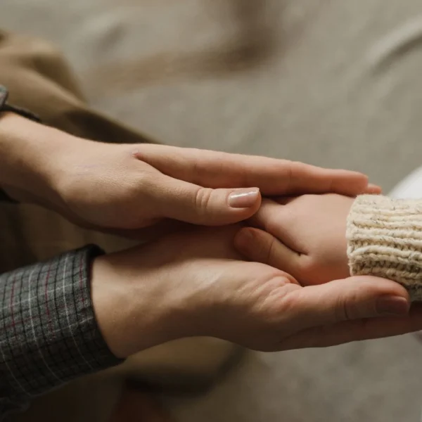 a mother’s hands cupping her child’s hand