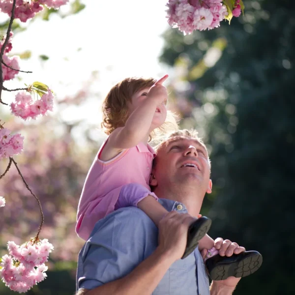 father gives her daughter a piggyback ride as they appreciate the flowers