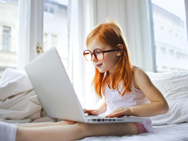 Kid using the computer on a bed
