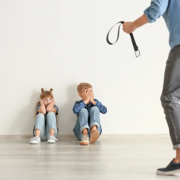 two children sitting on the floor while their father takes out his belt